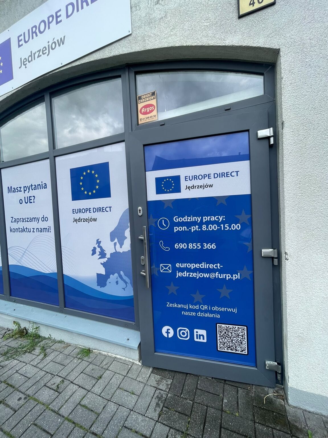 Wejście do punktu EUROPE DIRECT Jędrzejów z informacją o godzinach pracy i danych kontaktowych.